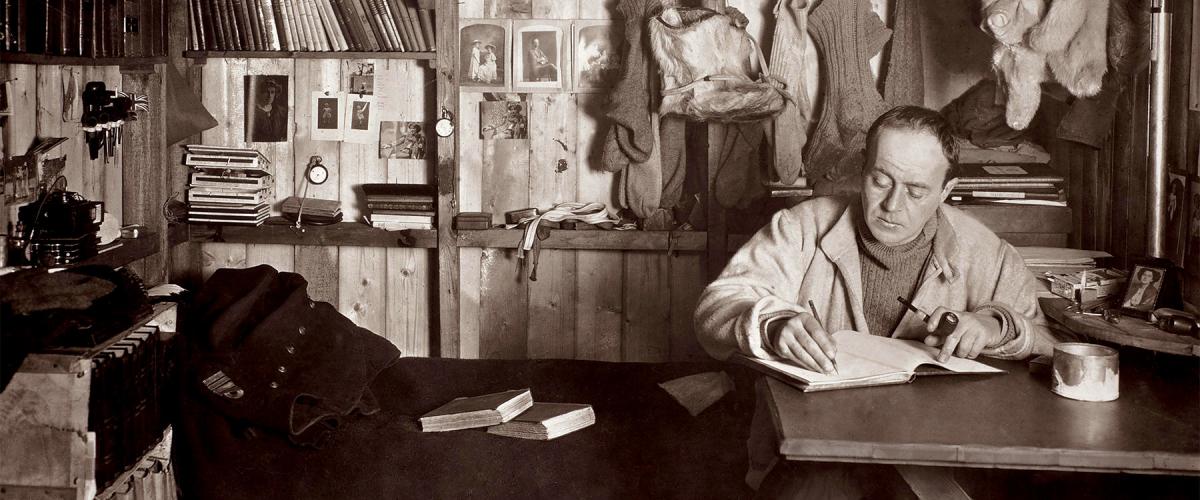 Captain Robert Falcon Scott writing in his diary in his Cape Evans hut